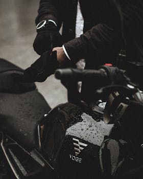 Close-up of a motorcyclist wearing gloves while preparing for a ride in the rain.