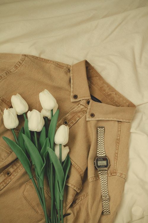 Free White tulips elegantly placed on a brown jacket with a wristwatch, perfect for lifestyle and fashion themes. Stock Photo