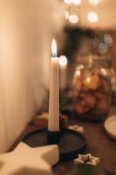 A soft-focus image of a lit candle on a table, creating a cozy atmosphere with blurred holiday decor.