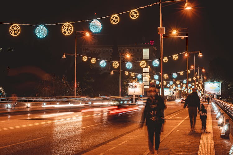 People Walking Illuminated Bridge At Night