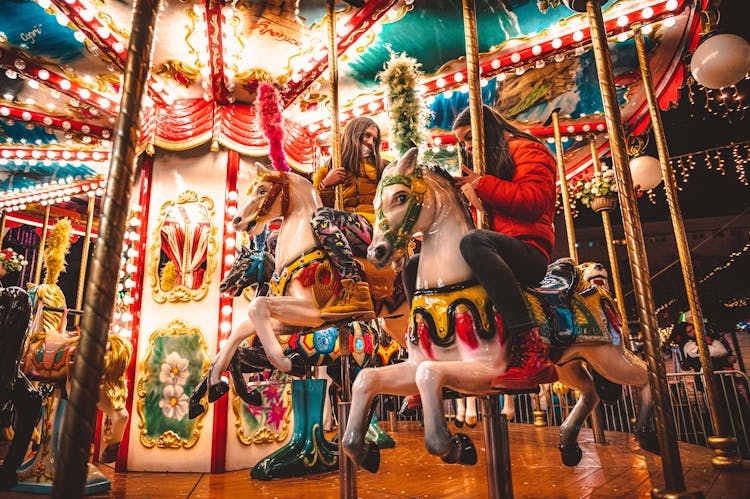 Two Women Riding A Carousel