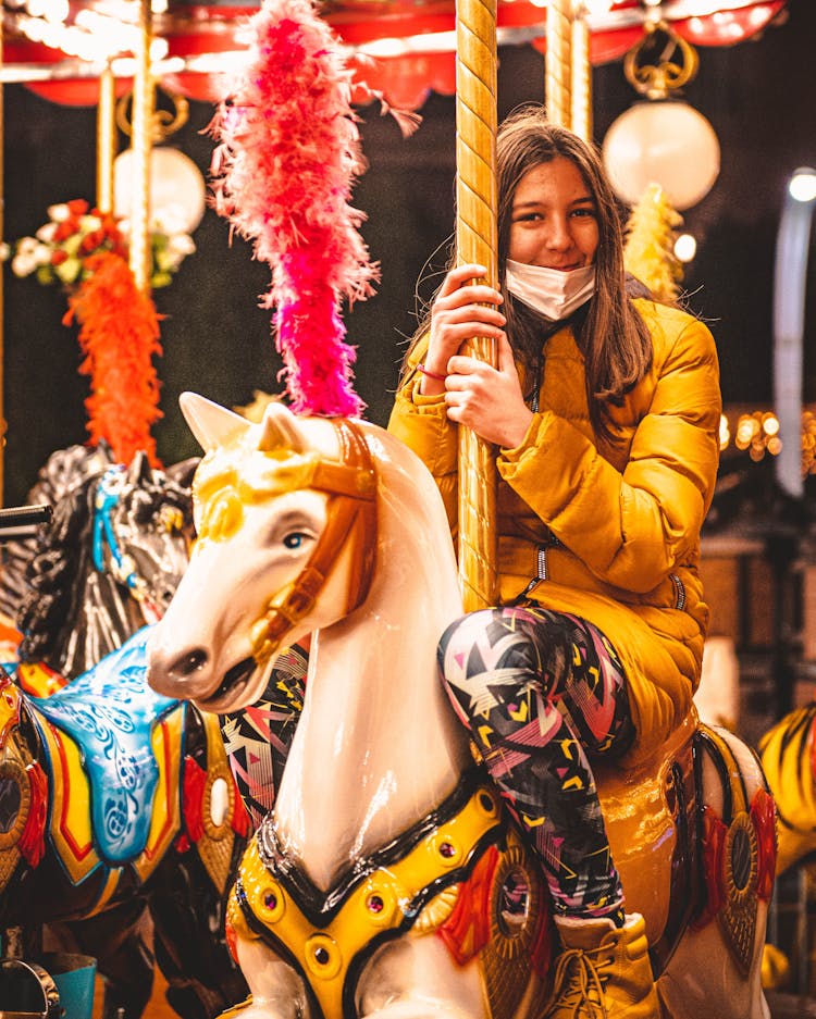 A Woman In Puffer Jacket Riding On A Horse Carousel