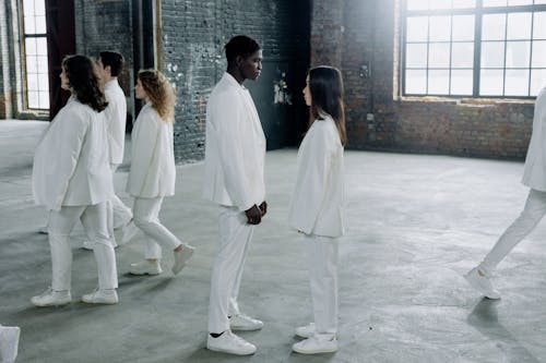 A Group of People in White Clothes Standing and Walking Inside the Building