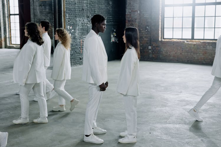 A Group Of People In White Clothes Standing And Walking Inside The Building