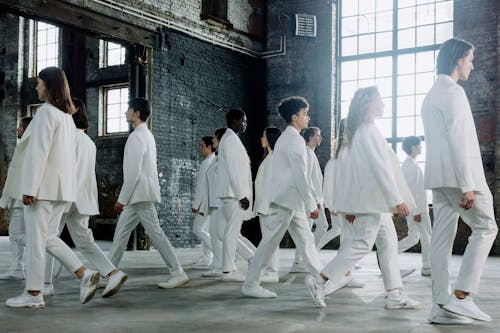 Group of People in White Clothes walking pass each other 