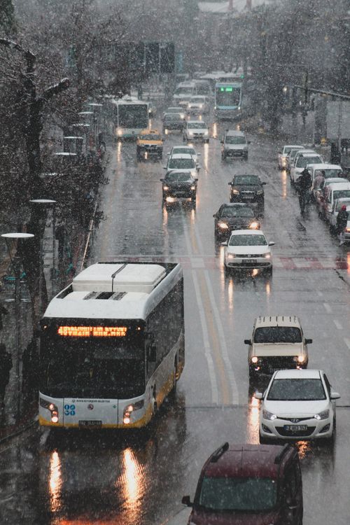 Free Busy city street with cars and bus during rainy day, capturing urban transportation. Stock Photo
