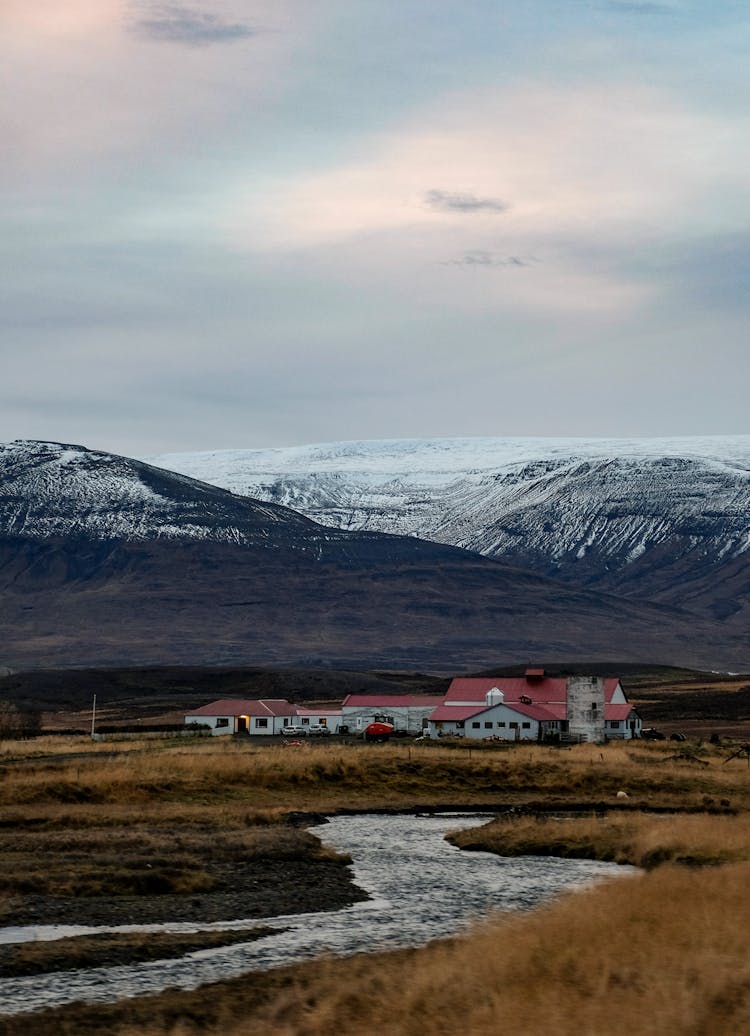 Farm Buildings Near River In Mountains