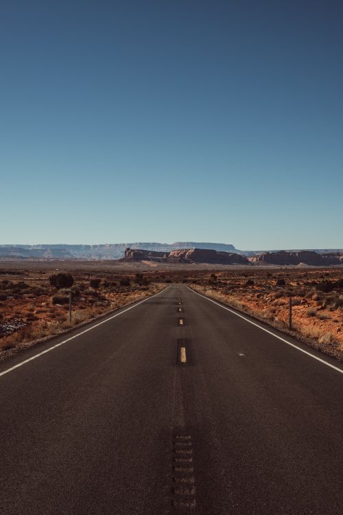 Free Vast desert highway with rock formations, perfect for travel and adventure themes. Stock Photo