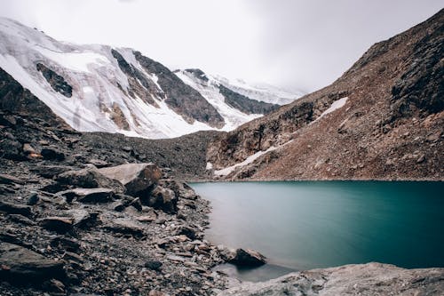 Lake Surrounded with Barren Mountains Covered with Snow