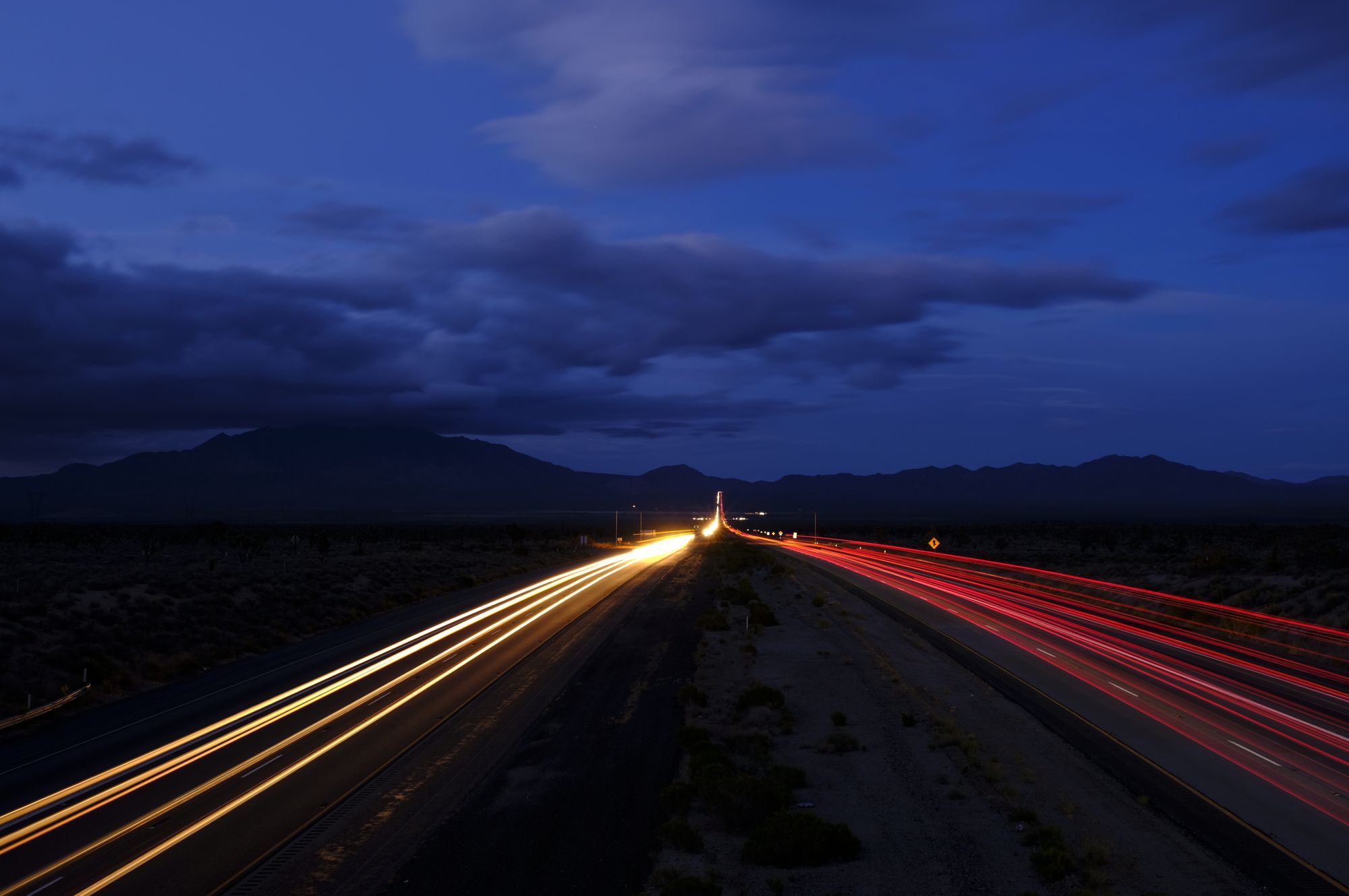 Long-exposure light trails along a desert highway at dusk — photo by Vitaly Kushnir on Pexels