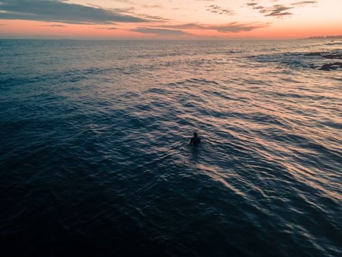 Free A lone swimmer enjoys the tranquil ocean at sunset in Punta del Este, Uruguay. Stock Photo