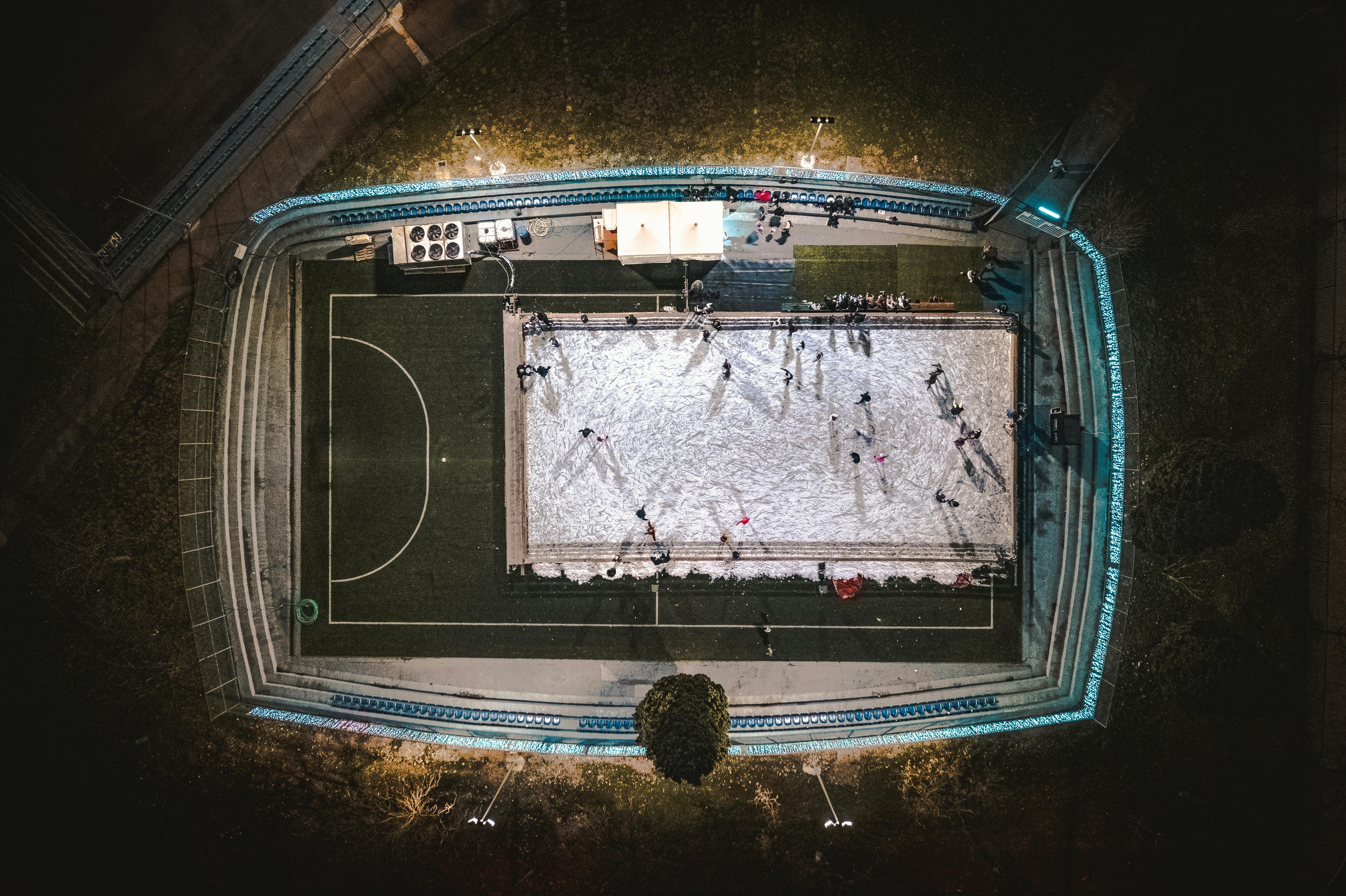 Aerial shot of a snowy stadium at night with people skating, showcasing winter sports in Podgorica, Montenegro.