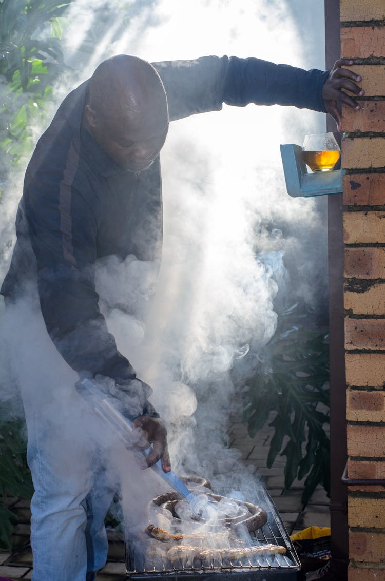 A Man In Black Jacket Grilling A Food