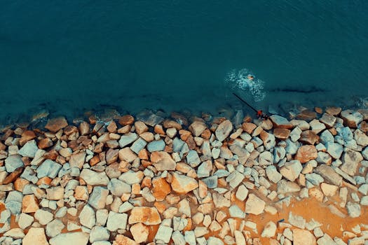 从空中俯瞰，岩石海岸线、绿松石般的海水和游泳者尽收眼底，展现了大自然的美丽