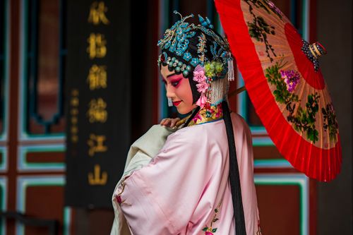 Free Portrait of an Asian woman in traditional opera attire with an ornate headdress and colorful umbrella. Stock Photo