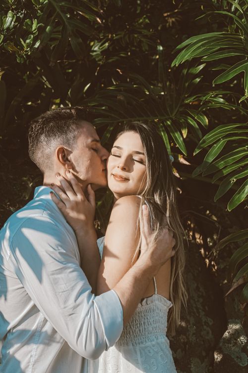 Free A loving couple shares a tender moment surrounded by lush tropical greenery in daylight. Stock Photo