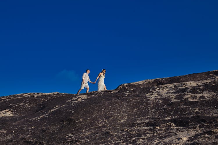 A Couple Walking On Top Of A Rocky Mountain