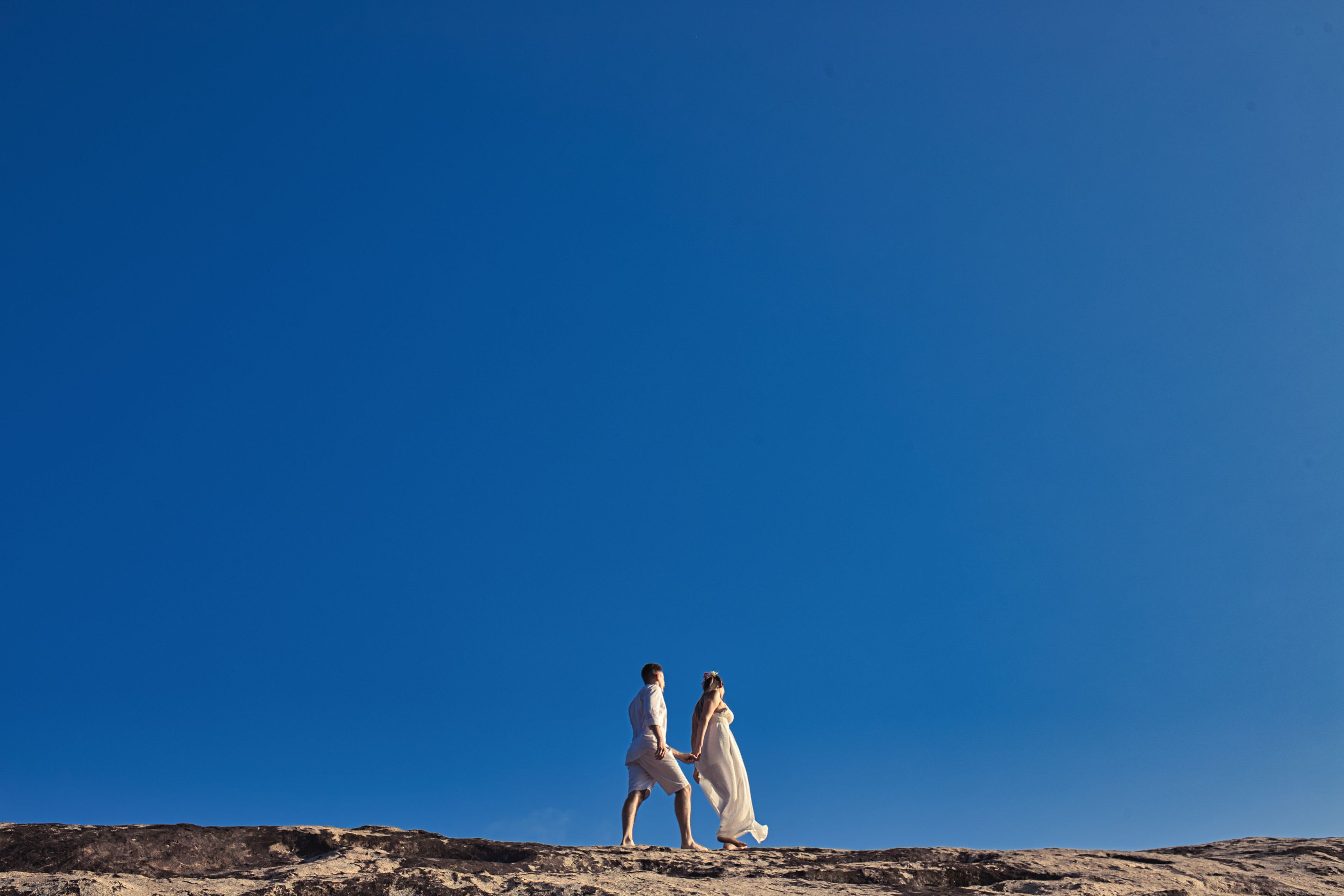 A Couple Holding Hands while Walking Under a Blue Sky · Free Stock Photo
