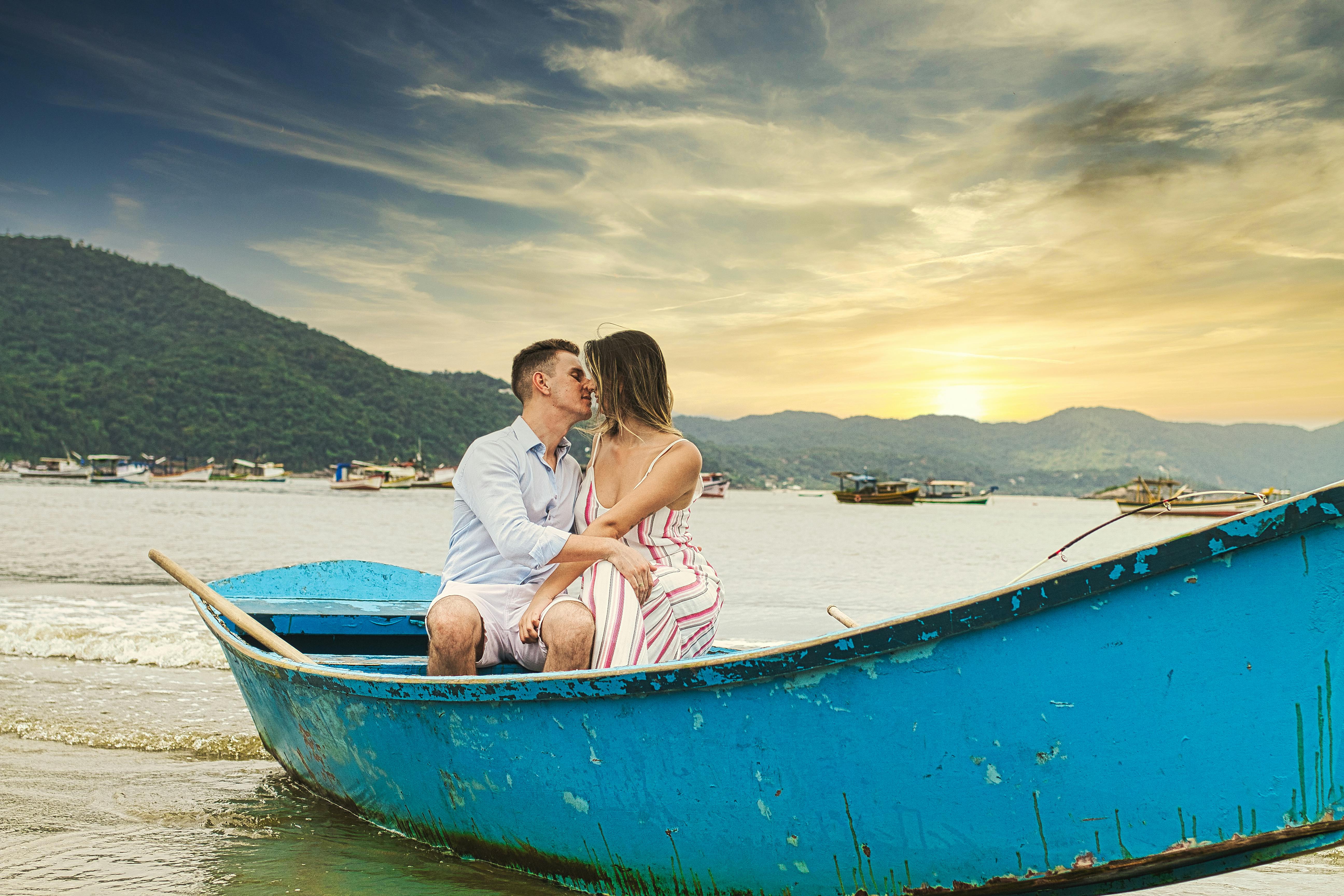 Casal em viagem romântica se beijando em barco ao pôr do sol, ideal para casais.