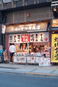 Japanese butcher shop with meat displays and bright signage on a city street.