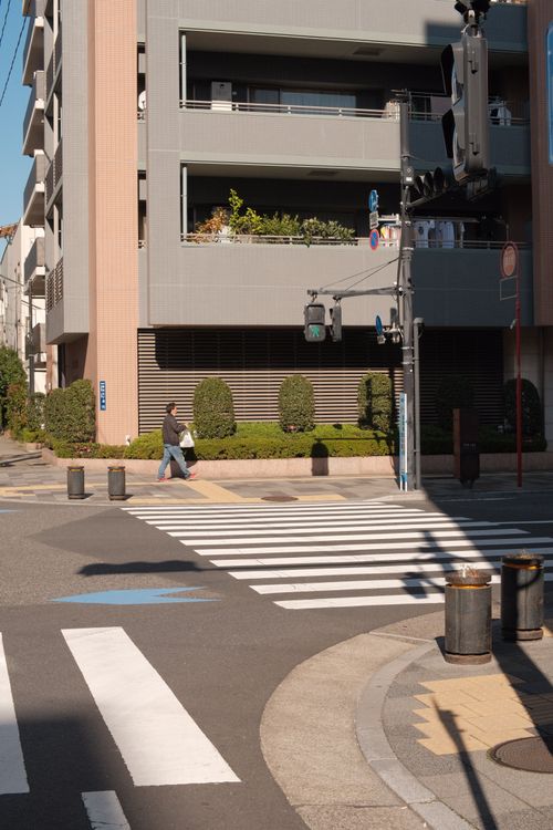 Free Man crossing an urban street in daylight with modern buildings. Stock Photo