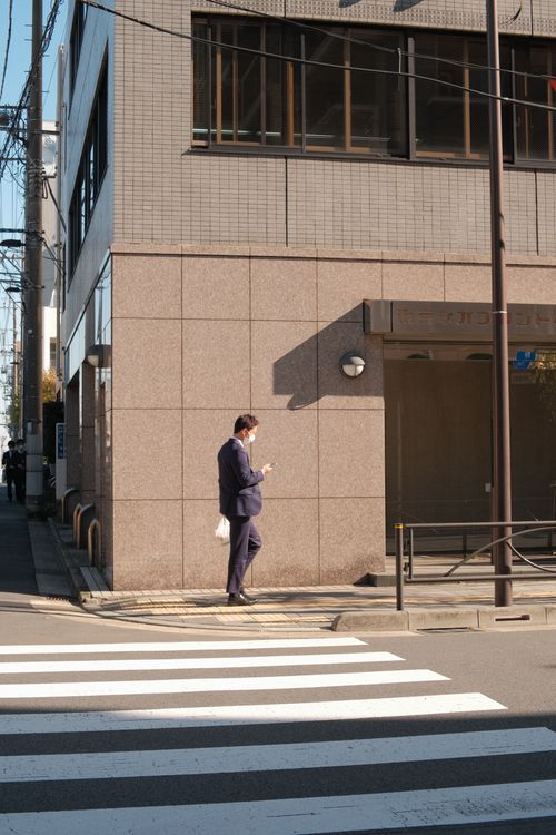 Free Businessman crossing street on sunny day with smartphone Stock Photo