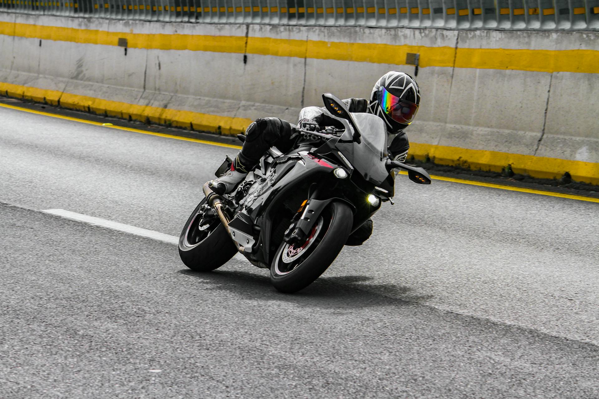 A motorcyclist leans into a turn on an urban road, showcasing speed and agility.