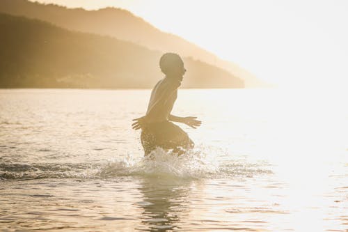 무료 낮 동안 물의 몸으로 돌진하는 소년 스톡 사진