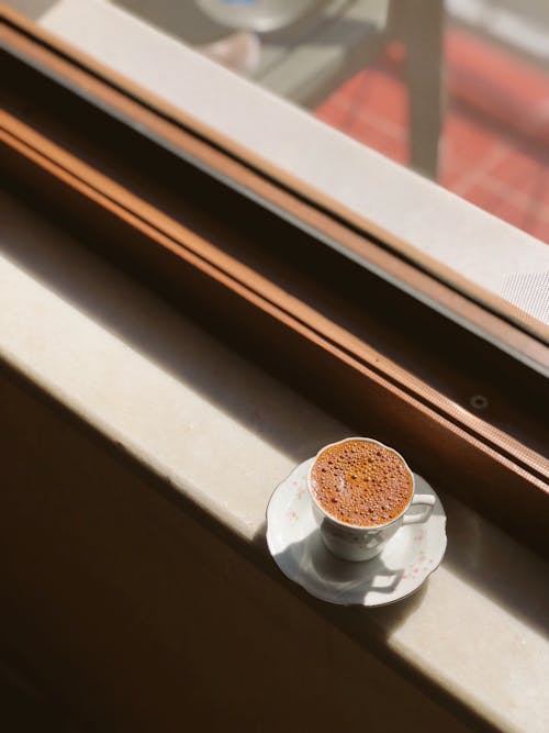 A Hot Coffee on a Ceramic Cup Near the Window