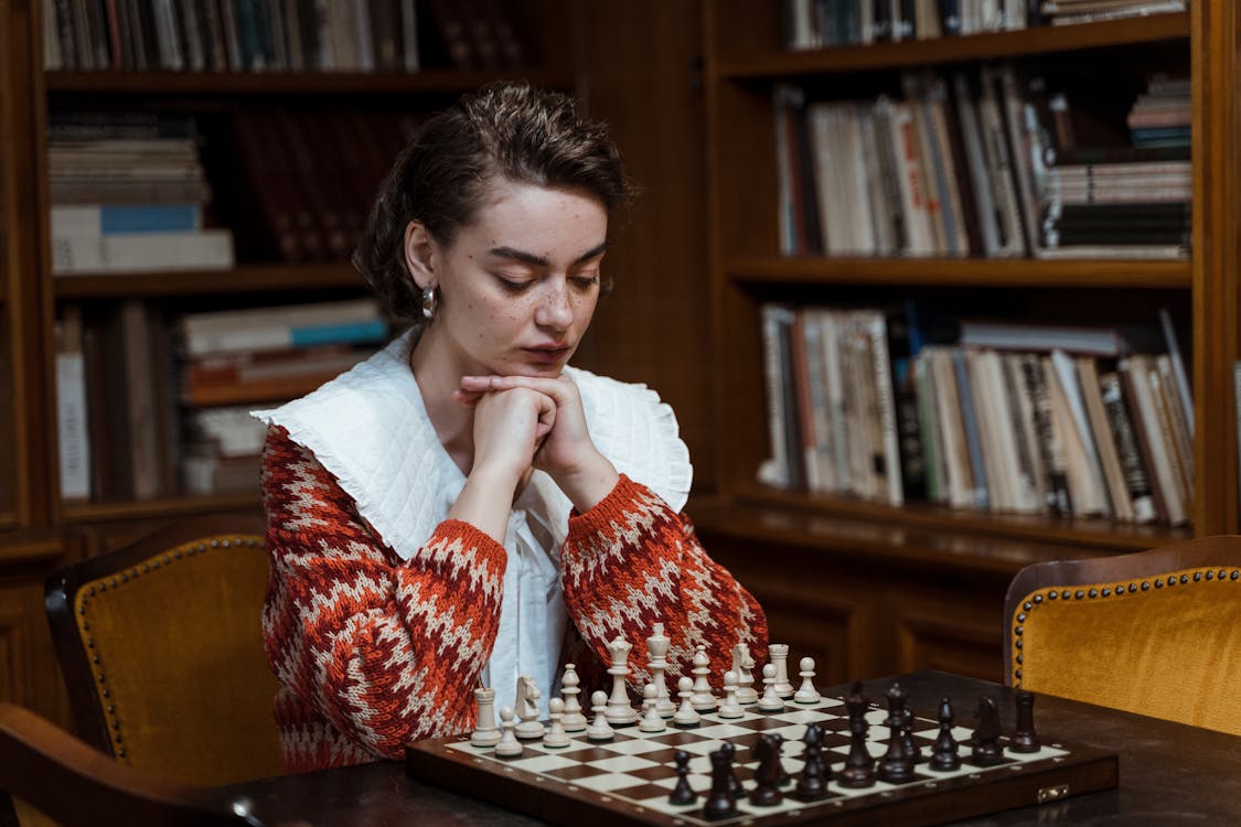 Pensive Woman looking at a Chess Set