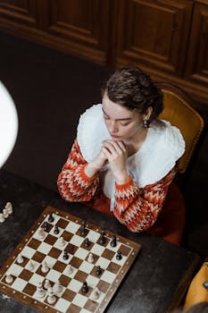 Woman deep in thought over a chessboard, planning her next strategic move.