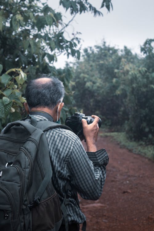 A Man Carrying a Backpack while Holding a Camera