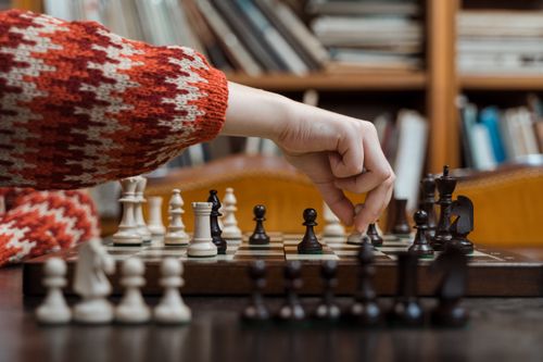 Free Close-up of a hand making a move on a chessboard in a cozy room, emphasizing strategy and focus. Stock Photo