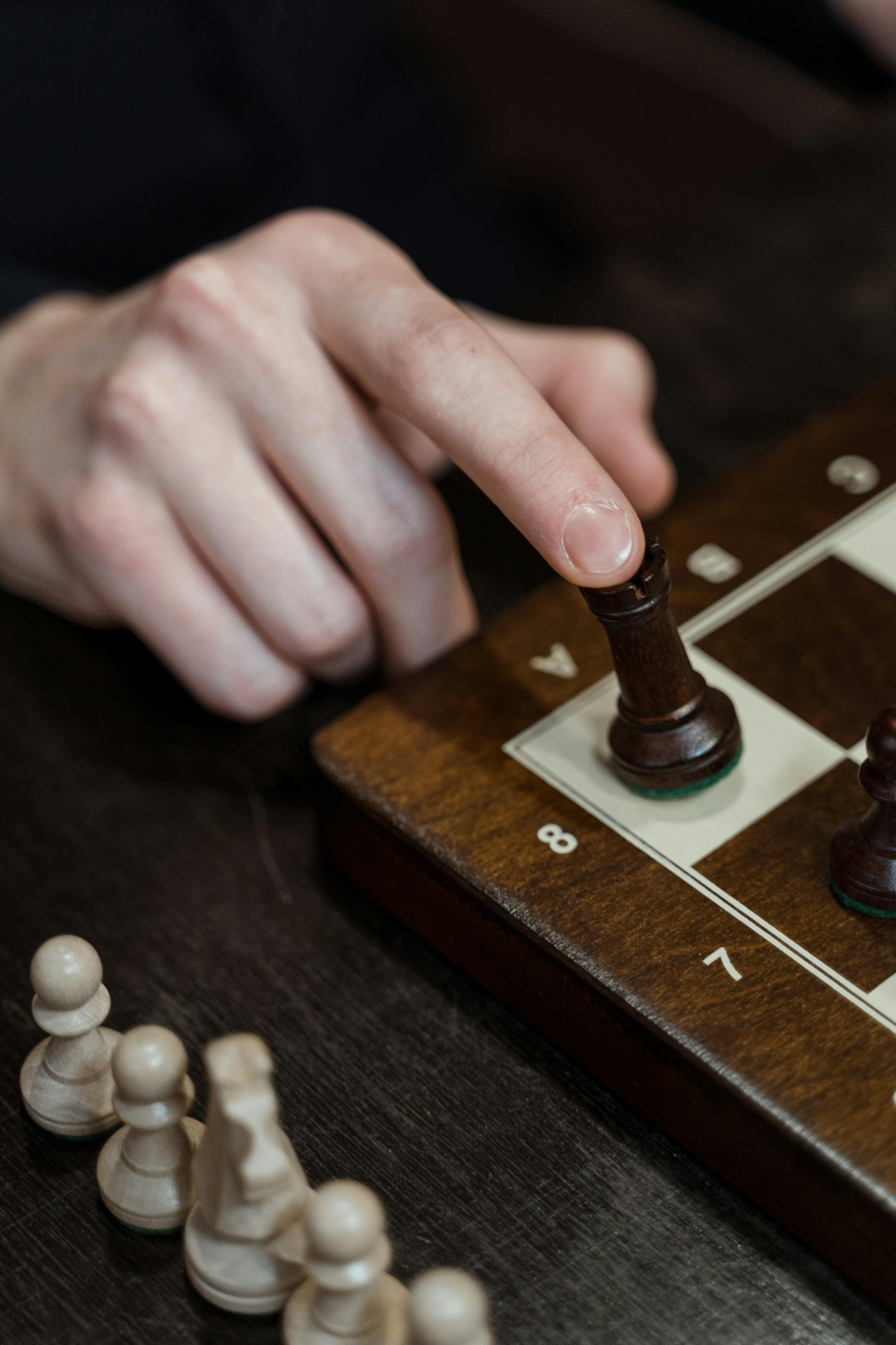 a person touching a chess piece