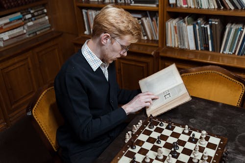 A Man Reading a Book Inside the Library
