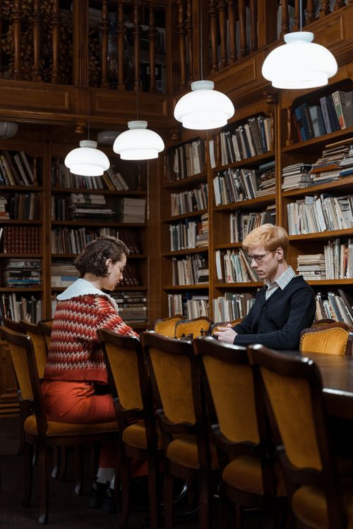 Free Two people engaged in thoughtful discussion in a classic library setting. Stock Photo