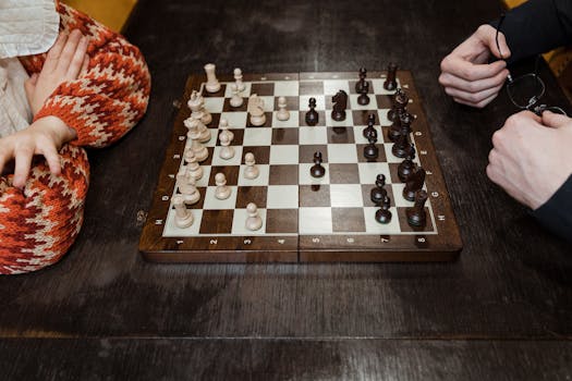 High angle view of chess game in progress with two players' hands showing strategic thinking.
