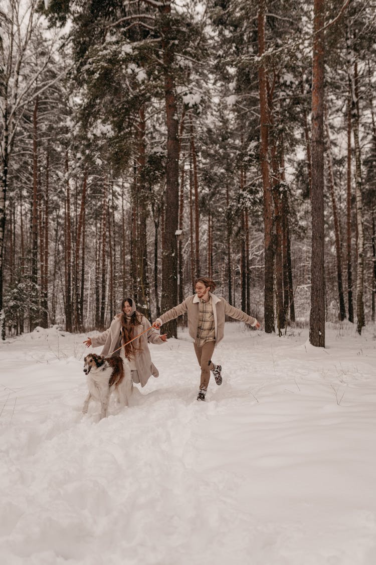 Couple And Dog Running In Snow 