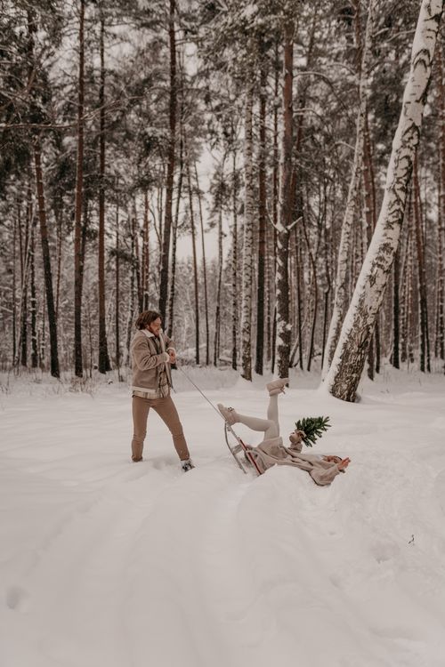 Free A happy couple enjoying a fun sled ride in a snowy winter forest. Perfect winter clothing and joy. Stock Photo