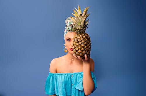 A Woman in Blue Off-Shoulder Top Holding a Pineapple