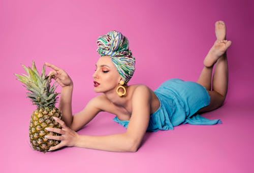 A Woman in Blue Dress Holding a Pineapple