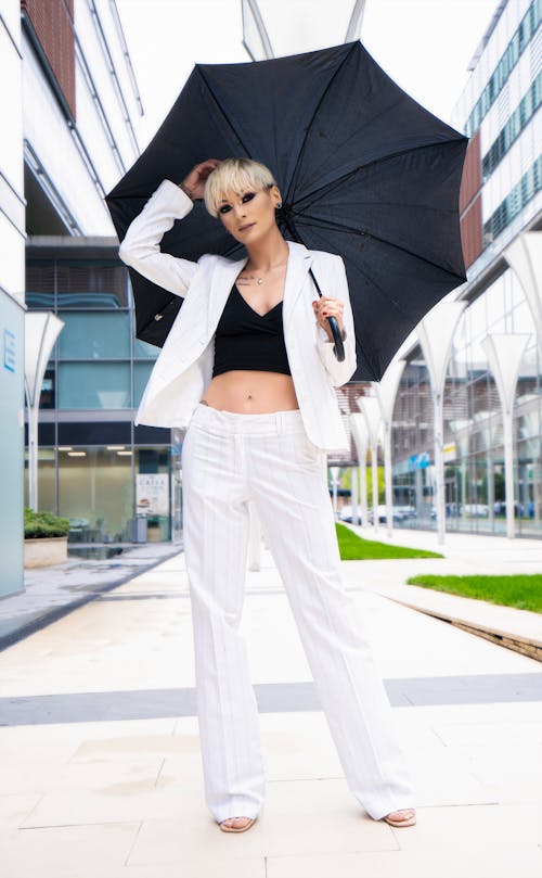 Stylish Woman in White Blazer and White Pants holding Black Umbrella 