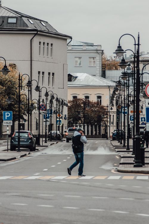 Free A person crossing a quiet urban street in autumn, capturing city life. Stock Photo