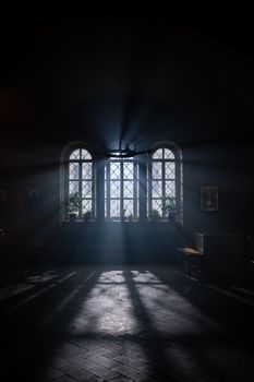 Dramatic church interior with sunlight streaming through windows, casting shadows on the floor.