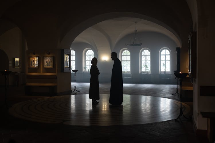 Silhouette Of Two People Talking In A Hallway