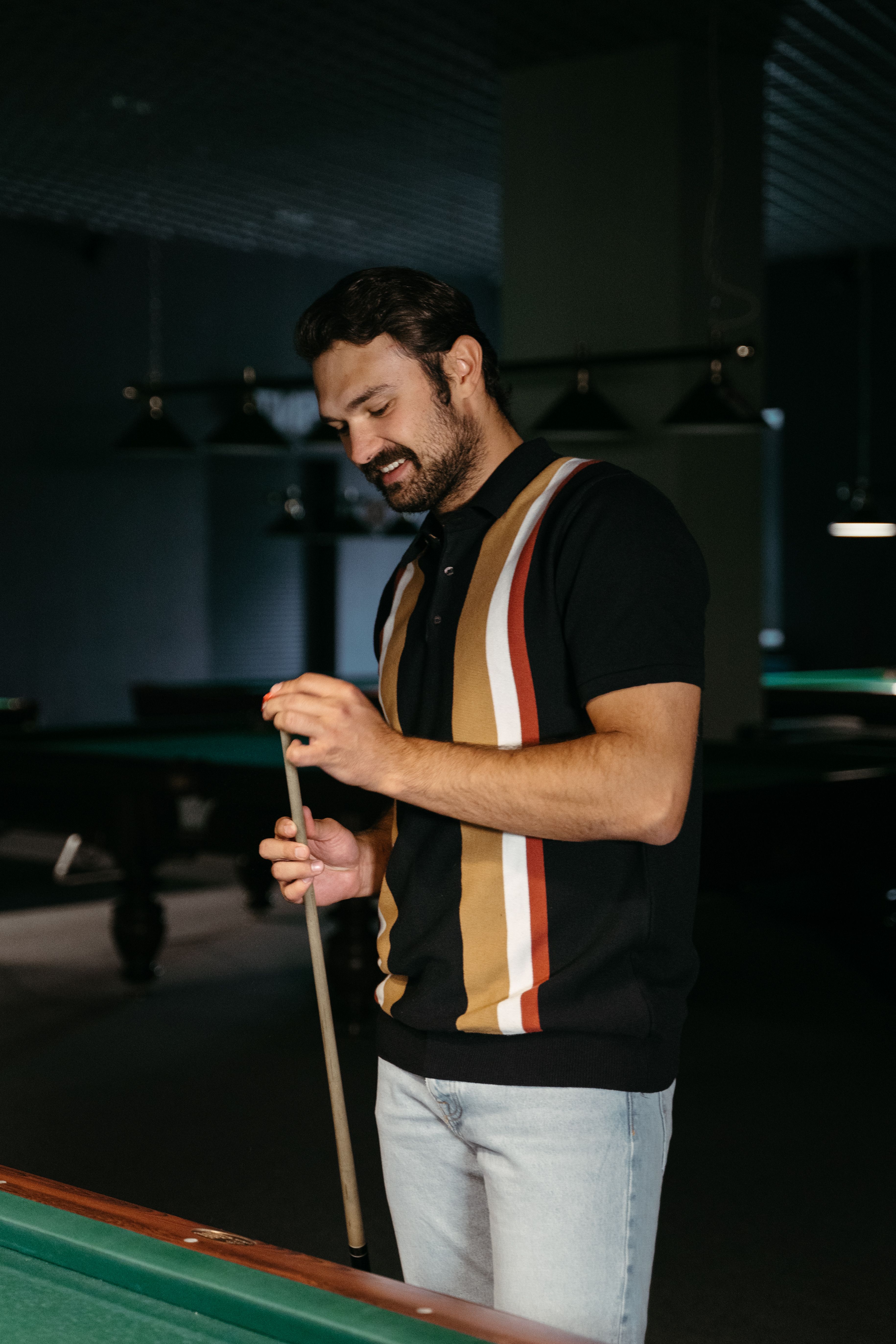 A man holds a cue stick while playing pool in a stylish billiard room.