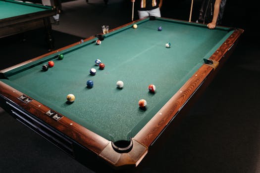 A close-up of a game in progress on a billiard table with colorful balls scattered.