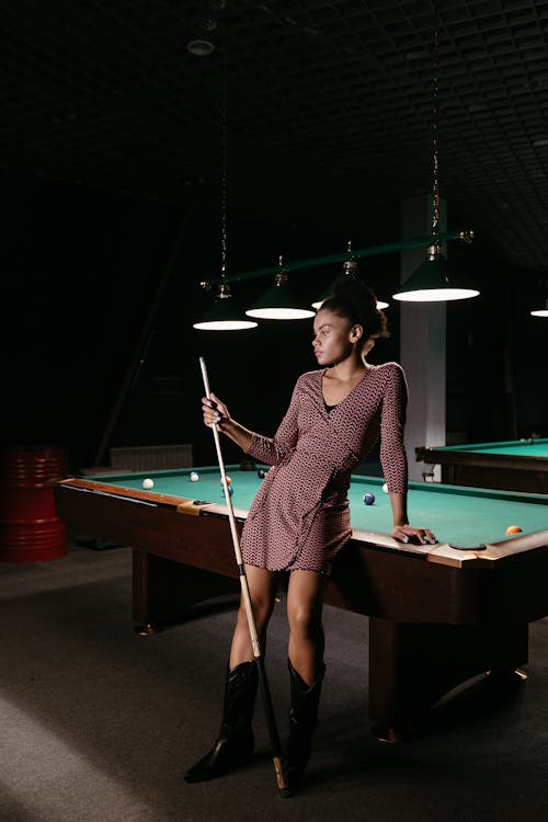 Free Woman in Purple and White Stripe Long Sleeve Mini Dress Standing on Pool Table Stock Photo