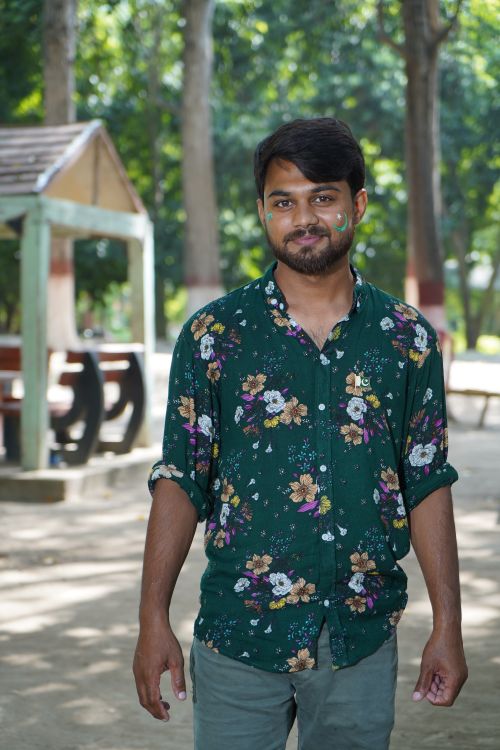 Free A young man in a floral shirt smiling outdoors in a park setting. Stock Photo