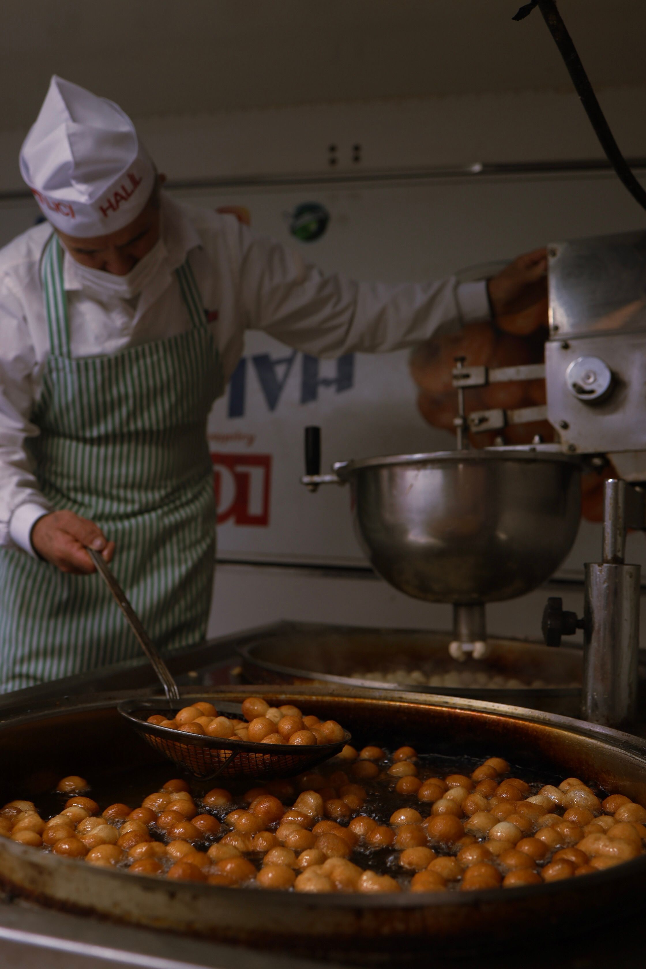 Chef preparing doughnuts in hot oil at a commercial kitchen. Perfect for food and culinary themes.